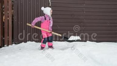 女孩，宝贝大铲子从车库女孩的后院的小路上移除雪，宝贝大铲子从小路上移除雪。